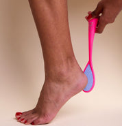 Main utilisant la râpe pieds céramique fluo rose Vitry double face gros et fins grains pour exfoliation douce 6075FZR sur son pied